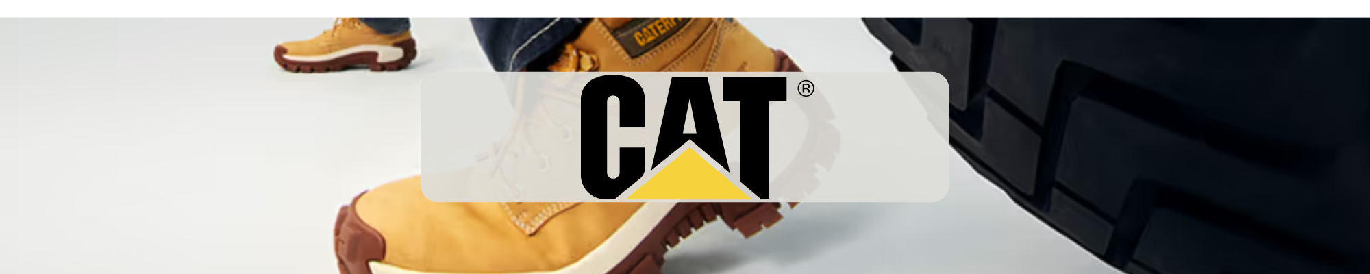 CAT logo over yellow work boots beside heavy equipment tire