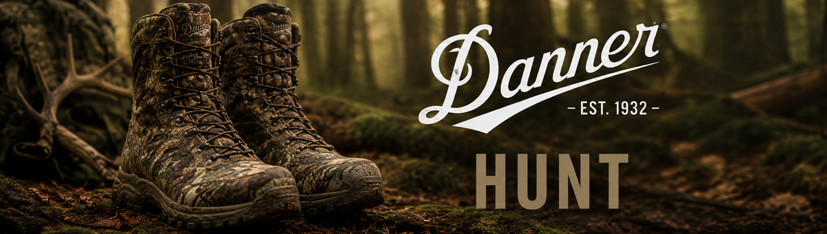 A pair of camouflage hunting boots resting on a forest floor with moss, twigs, and trees in the background. The words 'Danner - EST.
