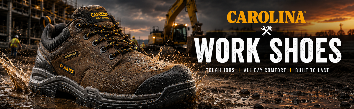 A brown and black Carolina Work Shoes sneaker shown in a muddy construction site setting with an excavator in the background.