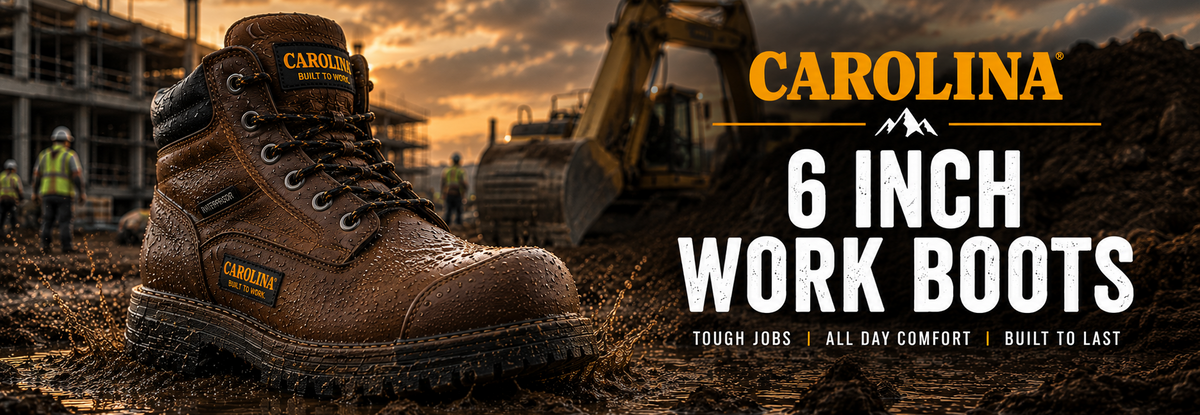 Pair of brown Carolina 6-inch work boots shown in a muddy construction site setting with an excavator in the background.