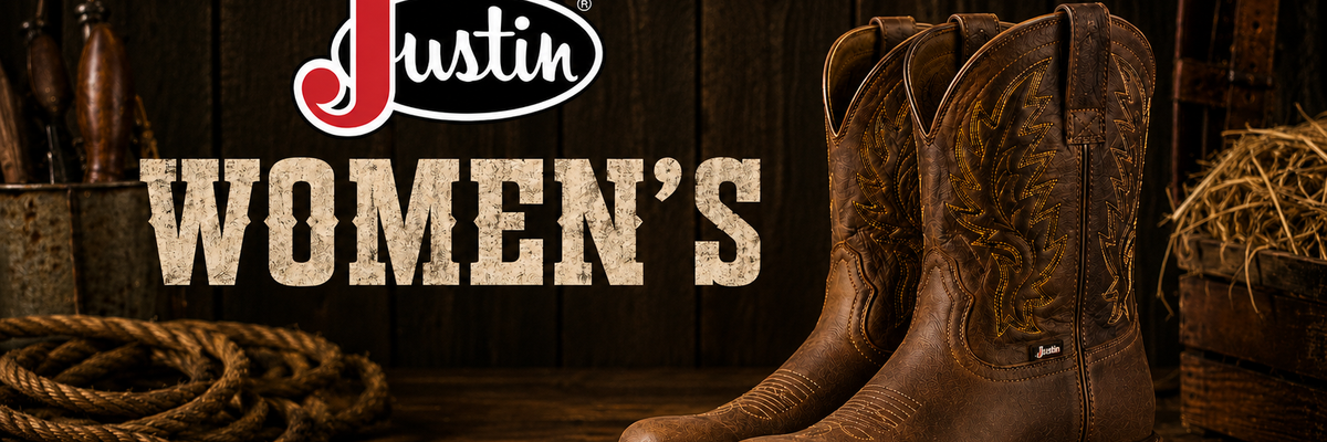 Pair of brown leather western boots with floral embroidery on the shafts, displayed on a rustic wooden surface with a coiled rope, hay, and tools in the background.