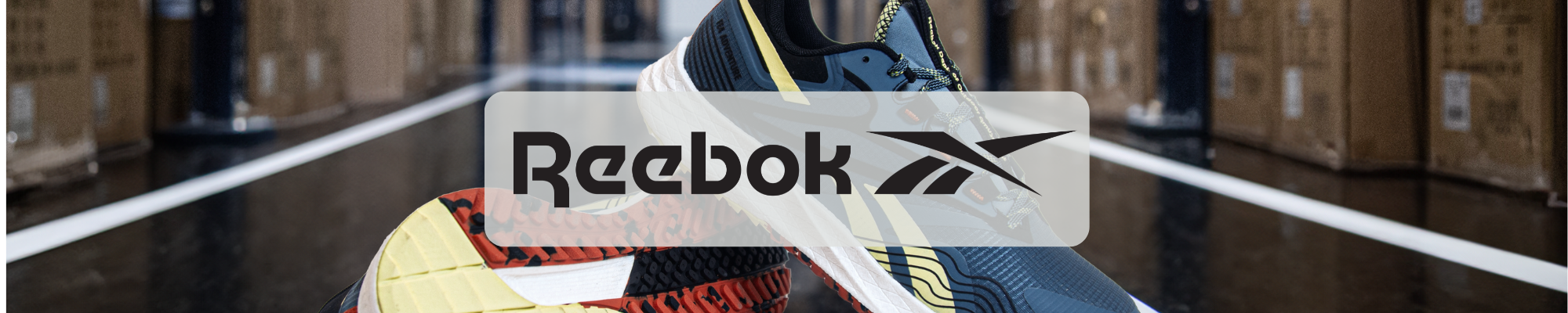 Reebok logo over blue and yellow work shoe in a warehouse aisle