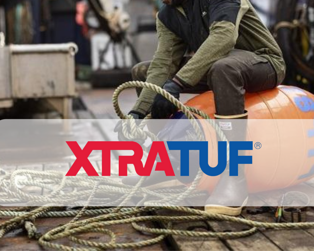 Commercial fisherman in Xtratuf rubber deck boots sitting on an orange buoy among coiled rope on a boat deck, with the Xtratuf logo overlaid