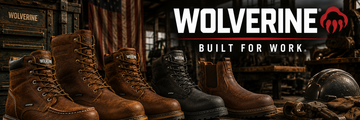 Four pairs of Wolverine work boots in brown and black leather are lined up on a rustic wooden workbench inside a workshop setting.