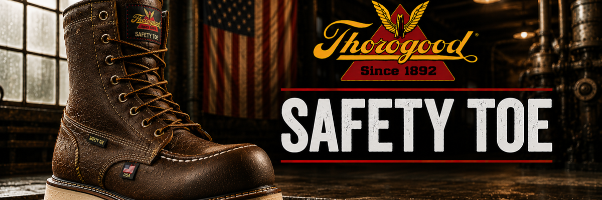 A brown leather safety boot with a thick white outsole is shown in a dark industrial setting with an American flag in the background.