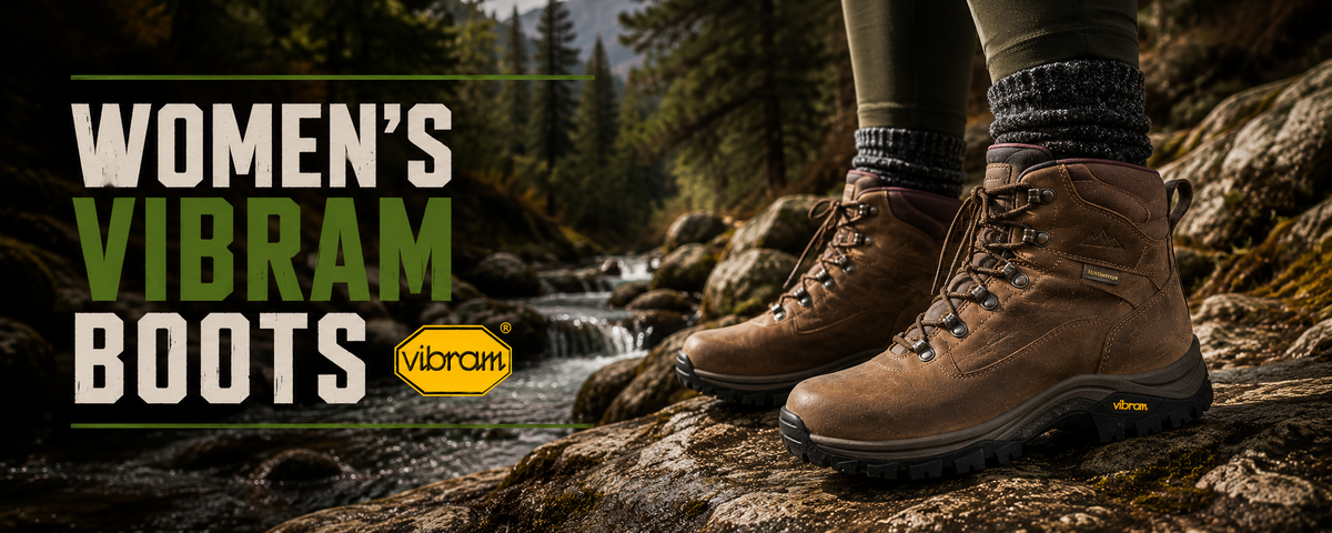 Pair of women's brown Vibram hiking boots worn on a person's feet, standing on rocks near a stream in a forest setting.