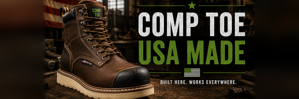 A brown leather Comp Toe work boot with a black toe cap and beige sole, displayed on a rustic wooden surface with a blurred workshop background and an American flag.