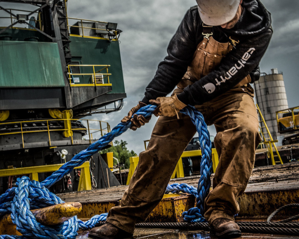  a man in oil boots is tying a rope on the structure